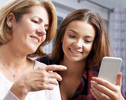 A Mom and Daughter Looking at a Phone and Smiling